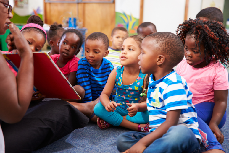 Teacher reading to group of children.